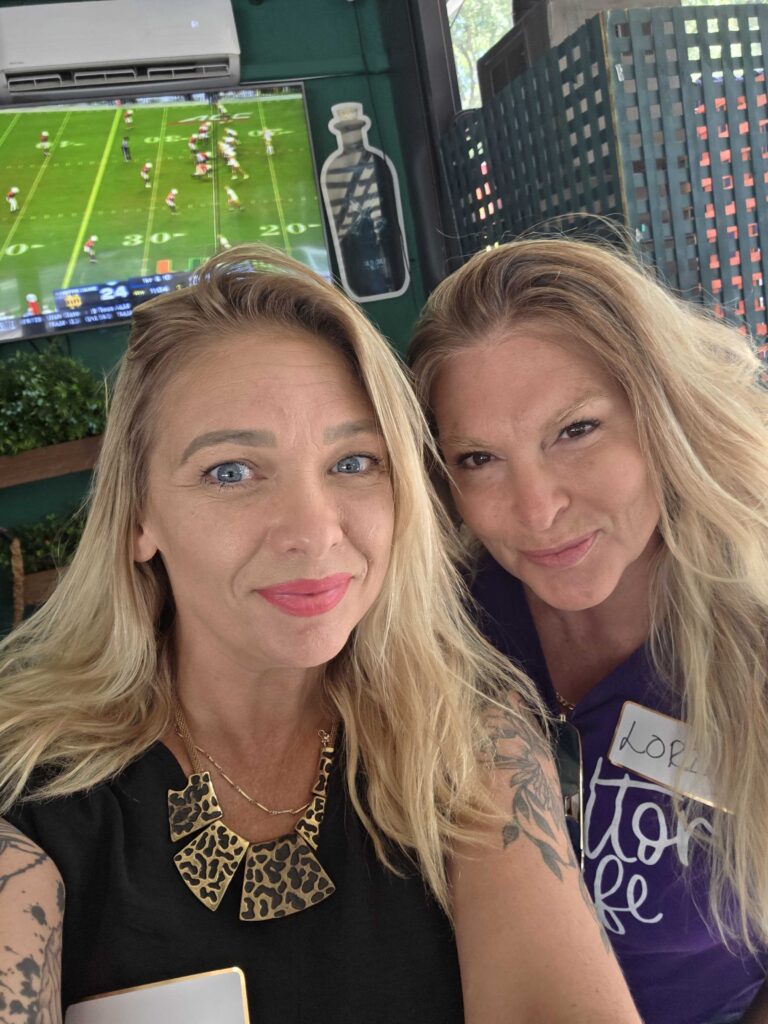 “Two women smiling together at a networking event, representing connection and community at Women’s Business Connections”