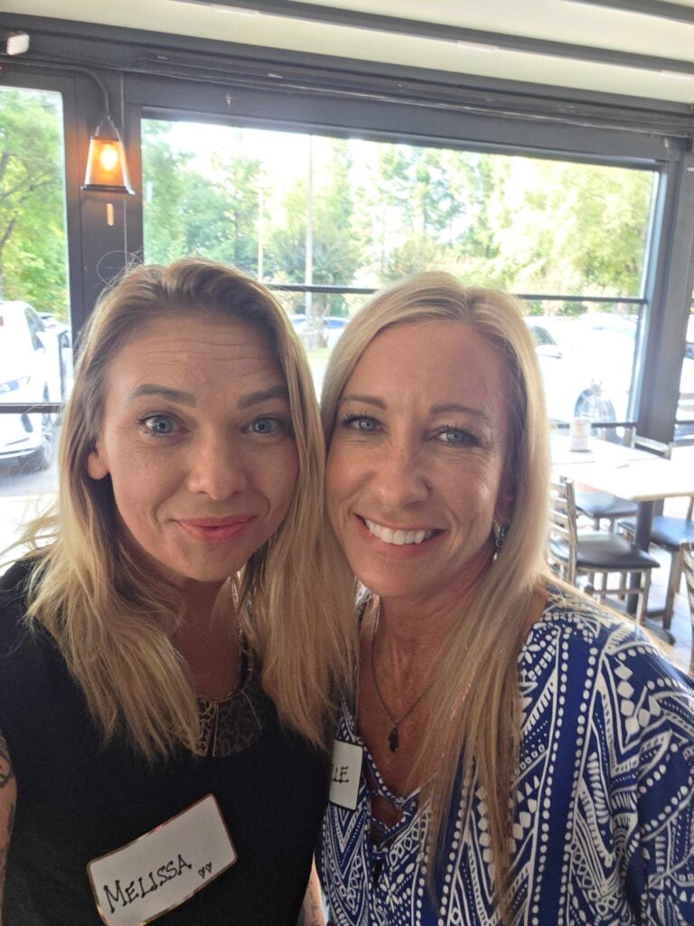 “Two women smiling together at a networking event, representing connection and community at Women’s Business Connections”