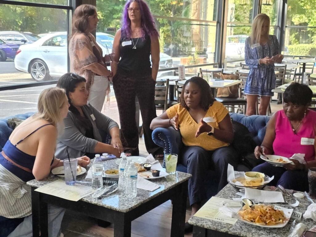 “Group of women networking and having a casual discussion at a social event, building connections at Women’s Business Connections”