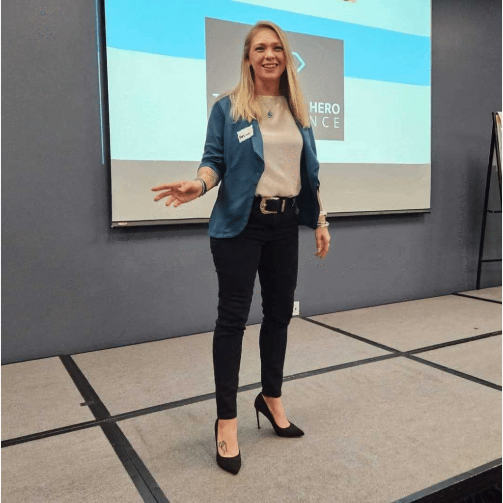 “Woman presenting on stage at a business event, representing leadership and public speaking at Women’s Business Connections”